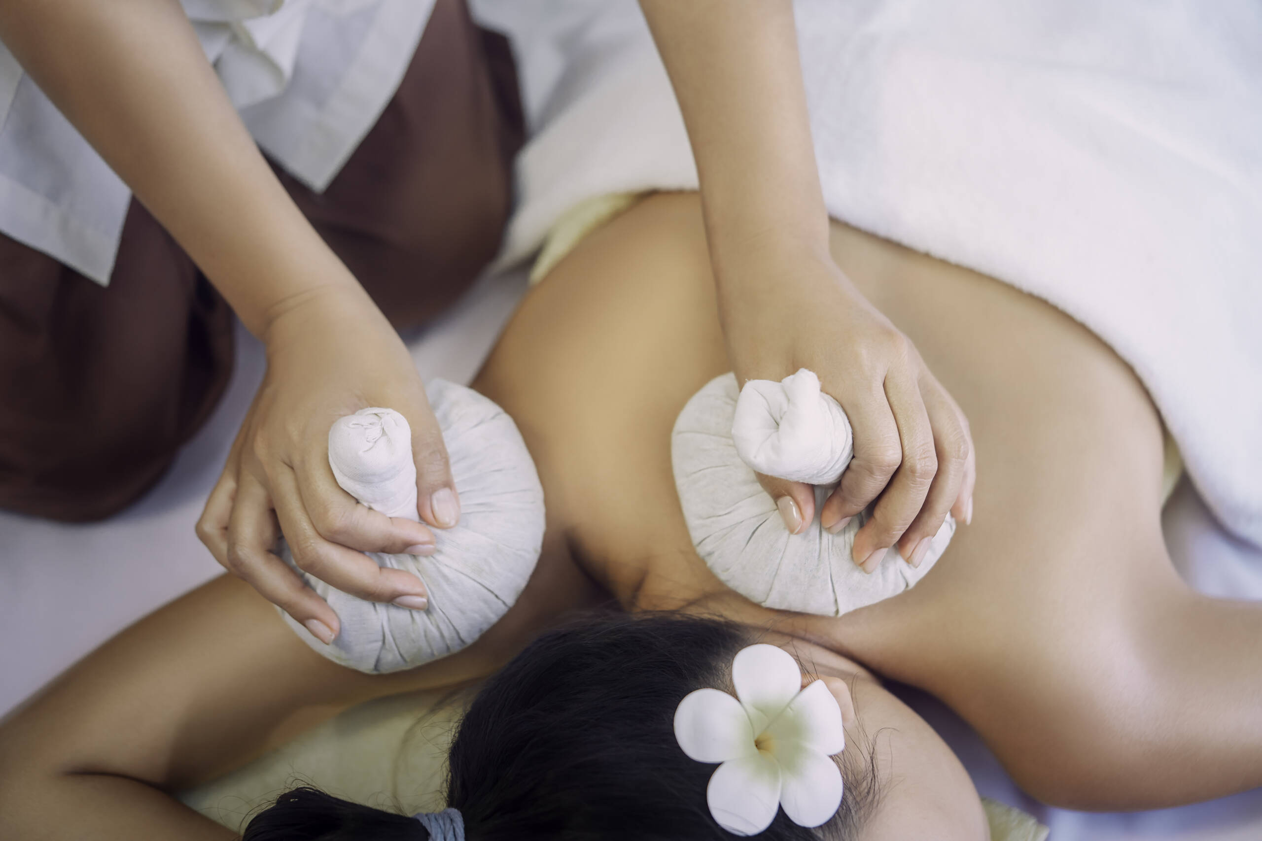 Young Asian woman is taking Thai Herbal ball hot compress massage in an authetic spa authentic